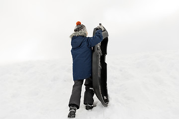 Image showing little boy with sled climbing snow hill in winter