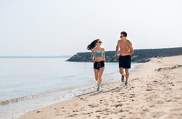 Image showing couple in sports clothes running along on beach