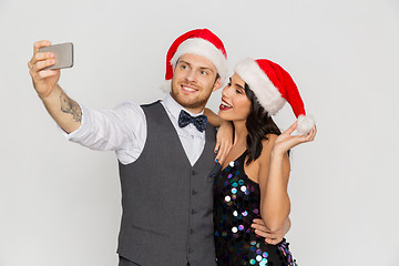 Image showing couple in santa hats aking selfie at christmas