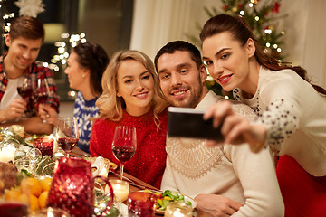 Image showing friends having christmas dinner and taking selfie