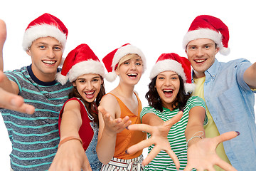 Image showing happy friends in santa hats over white background