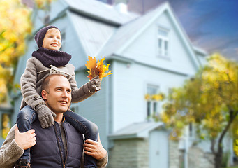 Image showing father and son with autumn maple leaves over house