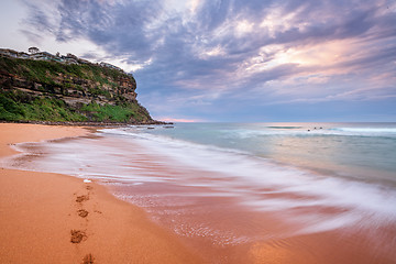 Image showing Waves wash on the seashore washing away footprints