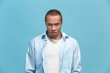 Image showing The young emotional angry man on blue studio background