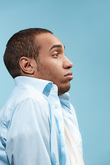 Image showing Doubtful Afro-American man is looking frightenedly against blue background