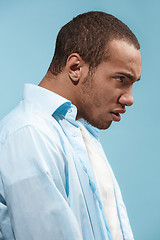 Image showing The young emotional angry man on blue studio background