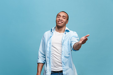 Image showing The happy business man standing and smiling against blue background.