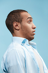 Image showing Doubtful Afro-American man is looking frightenedly against blue background