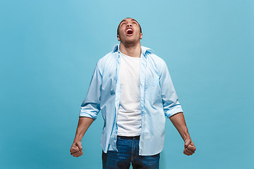 Image showing The young emotional angry man screaming on blue studio background