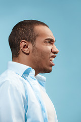 Image showing The young emotional angry man on blue studio background