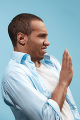 Image showing Young man with disgusted expression repulsing something, isolated on the blue