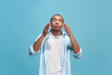 Image showing Beautiful male half-length portrait isolated on blue studio backgroud. The young emotional surprised man