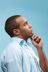 Image showing Thoughtful Afro-American man is looking thoughtfully against blue background