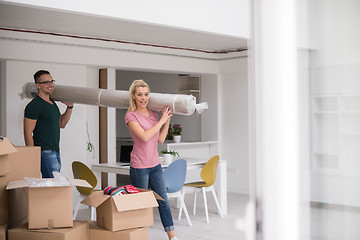 Image showing couple carrying a carpet moving in to new home