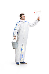 Image showing Young male decorator painting with a paint roller climbed a ladder isolated on white background.