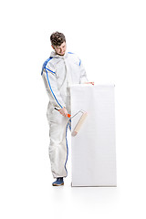 Image showing Young male decorator painting with a poster climbed a ladder isolated on white background.