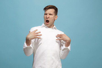 Image showing Beautiful male half-length portrait isolated on blue studio backgroud. The young emotional surprised man