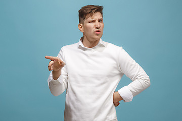 Image showing Young man with disgusted expression repulsing something, isolated on the blue