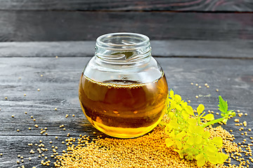 Image showing Oil mustard in jar with flower on board