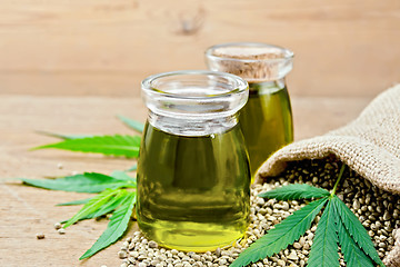 Image showing Oil hemp in two jars with sheet on wooden board
