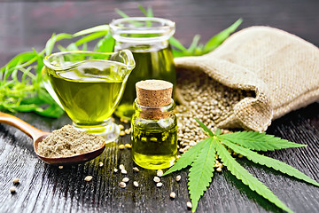 Image showing Oil hemp in two jars and sauceboat on wooden board