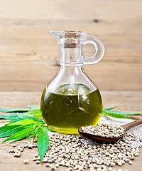 Image showing Oil hemp in glass decanter on board