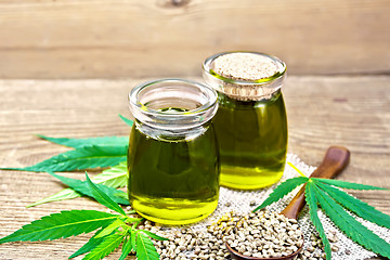 Image showing Oil hemp in two jars and spoon on old board