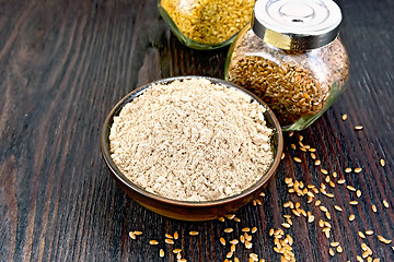 Image showing Flour linen in bowl with seeds in glass jars on dark board