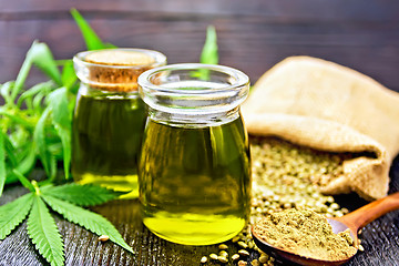 Image showing Oil hemp in two jars and flour in spoon on wooden table
