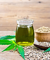 Image showing Oil hemp in jar with flour in bowl on board