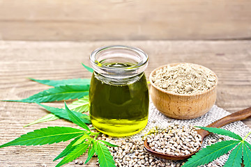 Image showing Oil hemp in jar with flour in bowl on wooden table