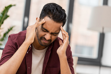 Image showing unhappy man suffering from head ache at home