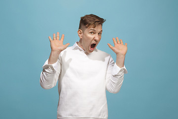 Image showing The young emotional angry man screaming on blue studio background