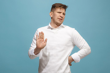 Image showing Young man with disgusted expression repulsing something, isolated on the blue