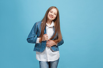 Image showing The happy teen girl standing and smiling against blue background.