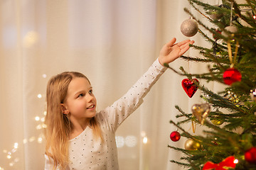 Image showing happy girl in red dress decorating christmas tree