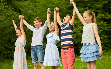 Image showing happy kids holding raised hands in summer park