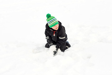 Image showing happy little boy playing with snow in winter