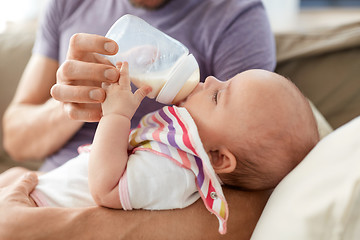 Image showing close up of father feeding baby from bottle