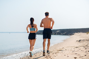 Image showing couple in sports clothes running along on beach