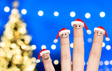 Image showing fingers in santa hats over christmas tree lights