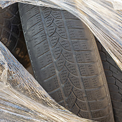 Image showing Worn out tires of heavy vehicles wrapped in plastic.