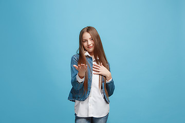 Image showing The happy teen girl with phone standing and smiling against pink background.