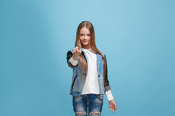 Image showing The happy teen girl pointing to you, half length closeup portrait on blue background.