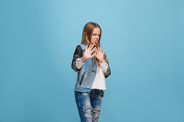 Image showing Doubtful pensive teen girl rejecting something against blue background
