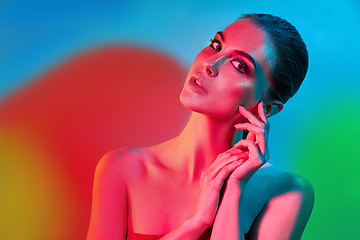 Image showing High Fashion model woman in colorful bright lights posing in studio