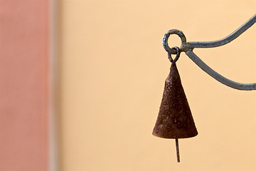 Image showing old rusty cone shaped bell hanging against blank wall