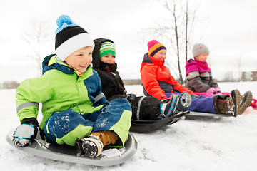 Image showing happy little kids sliding on sleds in winter