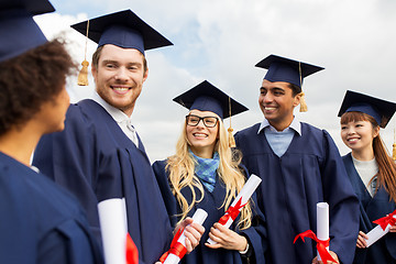 Image showing happy students in mortar boards with diplomas