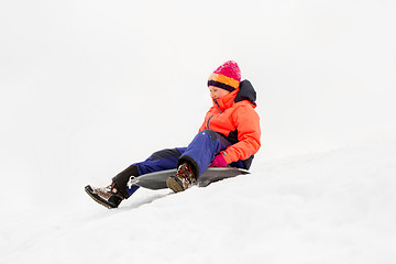 Image showing happy little girl sliding down on sled in winter